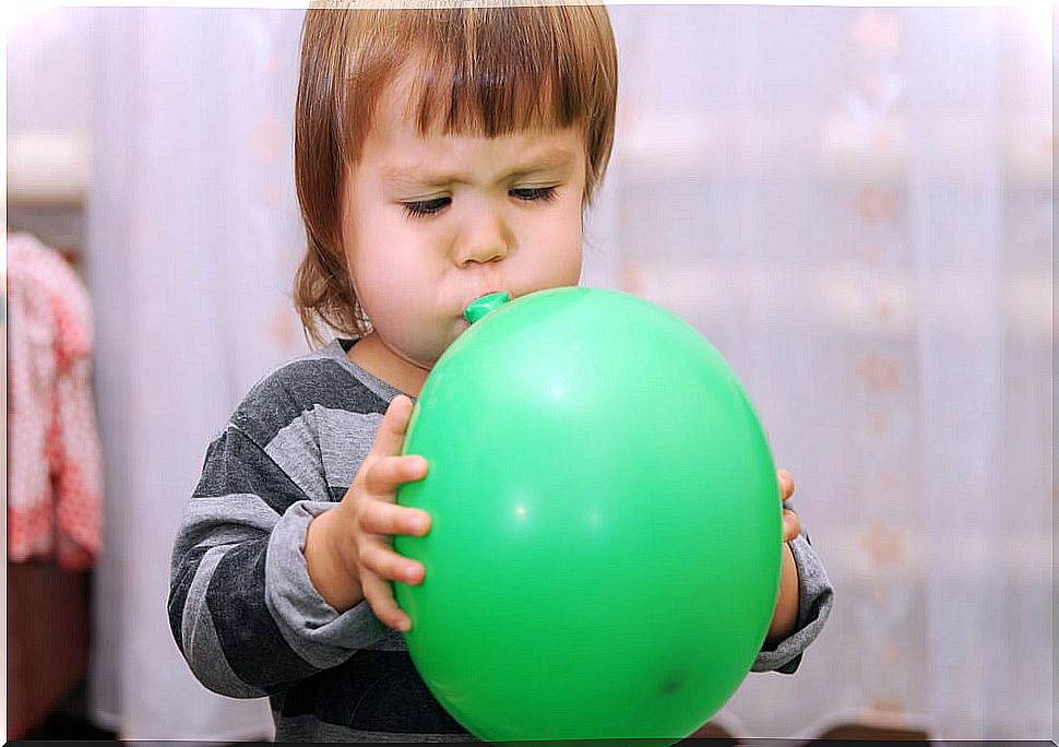 Girl blowing a balloon to stimulate language.