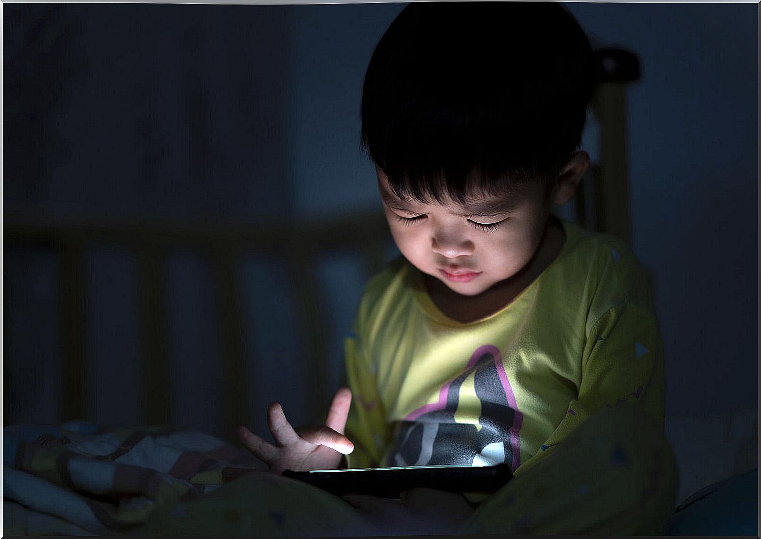 Child watching movies on mobile at night.