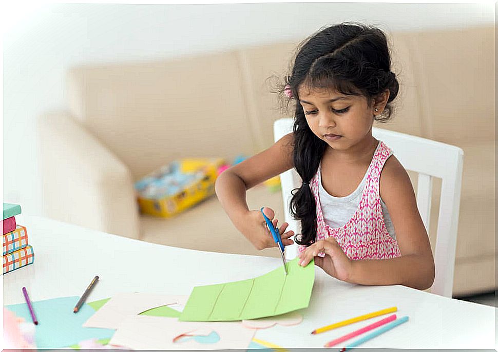 Girl cutting out a paper to overcome boredom and encourage her creativity.