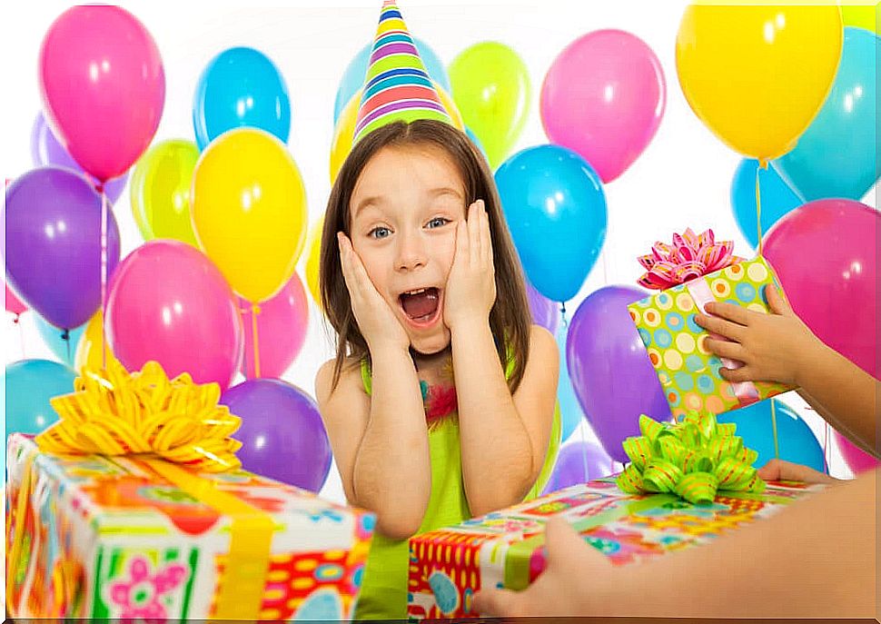 Little girl receiving many birthday gifts.