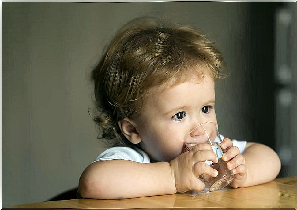 Baby drinking water from a glass.