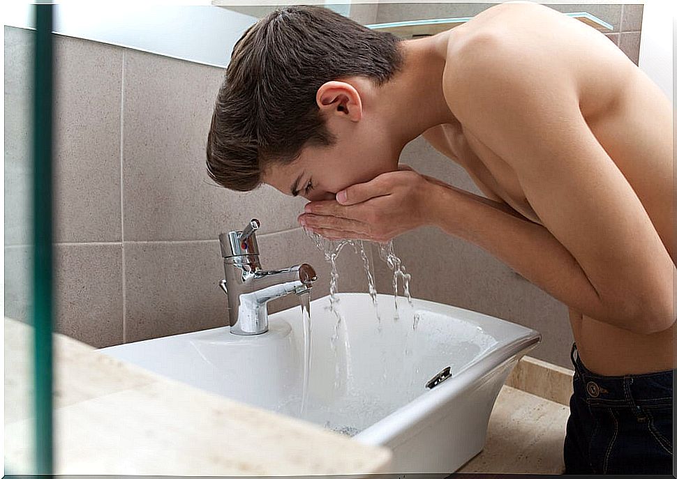 Teen boy rinsing off after brushing his teeth and using proper personal hygiene.