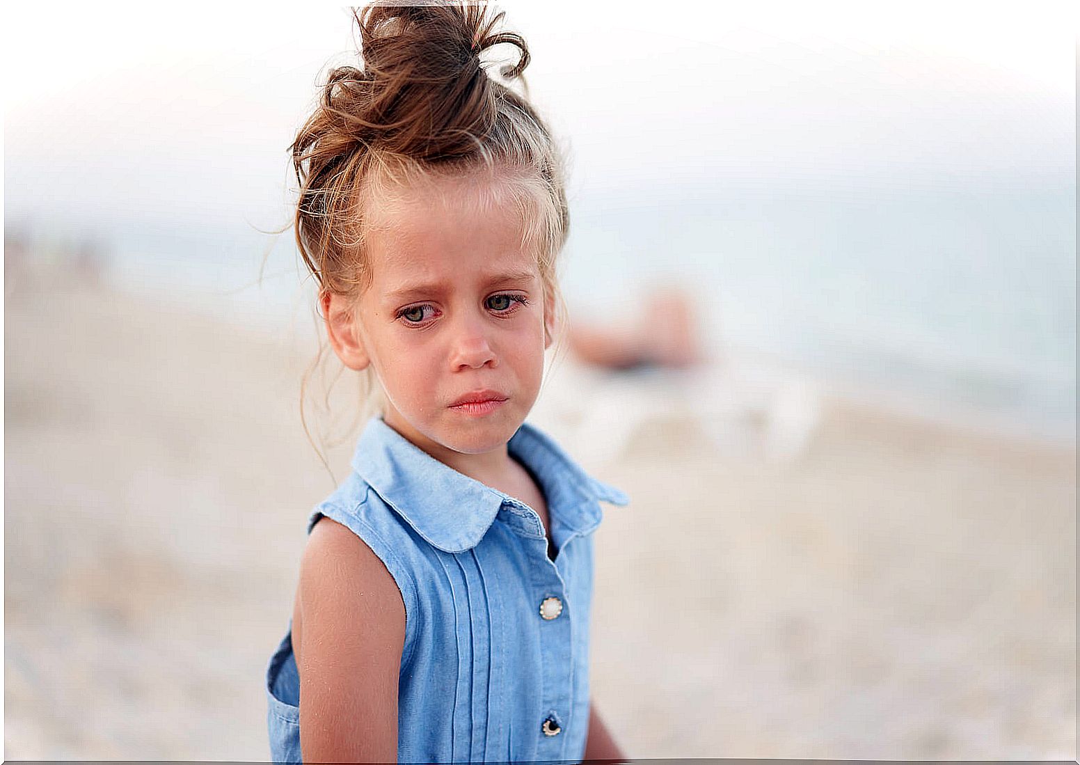 Girl crying on the beach because her parents find it difficult to recognize when a child is sad.