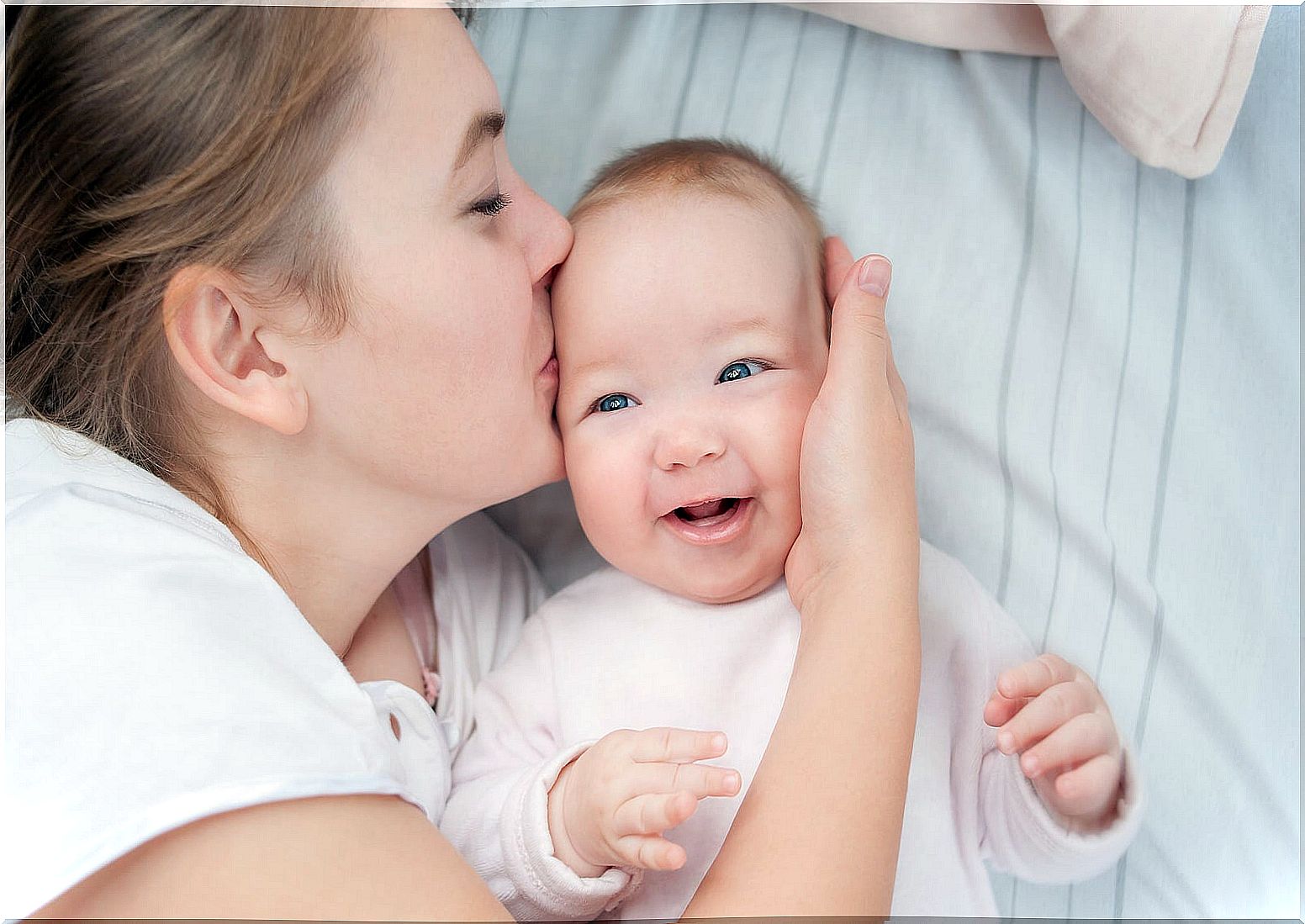 Mom giving her baby a kiss to stimulate him emotionally from birth.