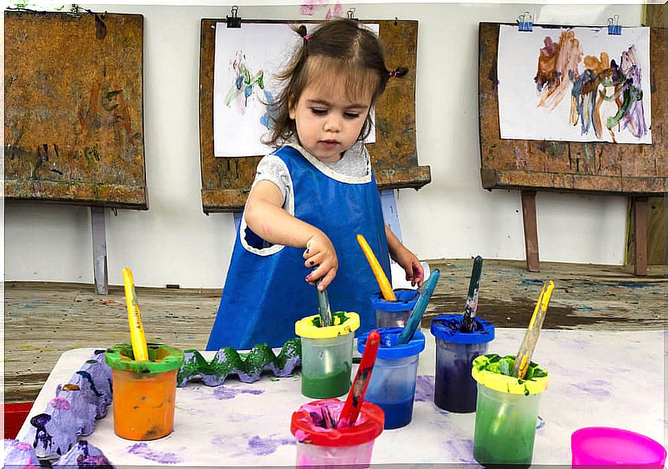 Little girl painting pictures to develop her artistic talent in preschool.