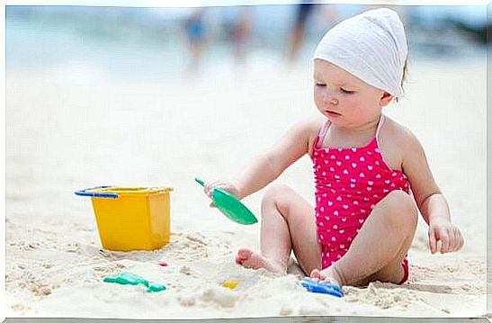 Cute baby girl playing with beach toys on tropical beach