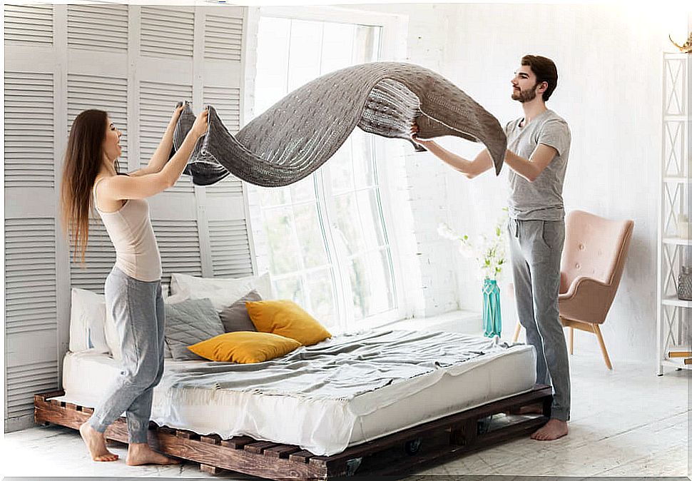 Couple making bed together.