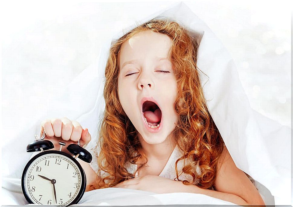 Girl turning off the alarm clock very sleepy to have a good day at school.