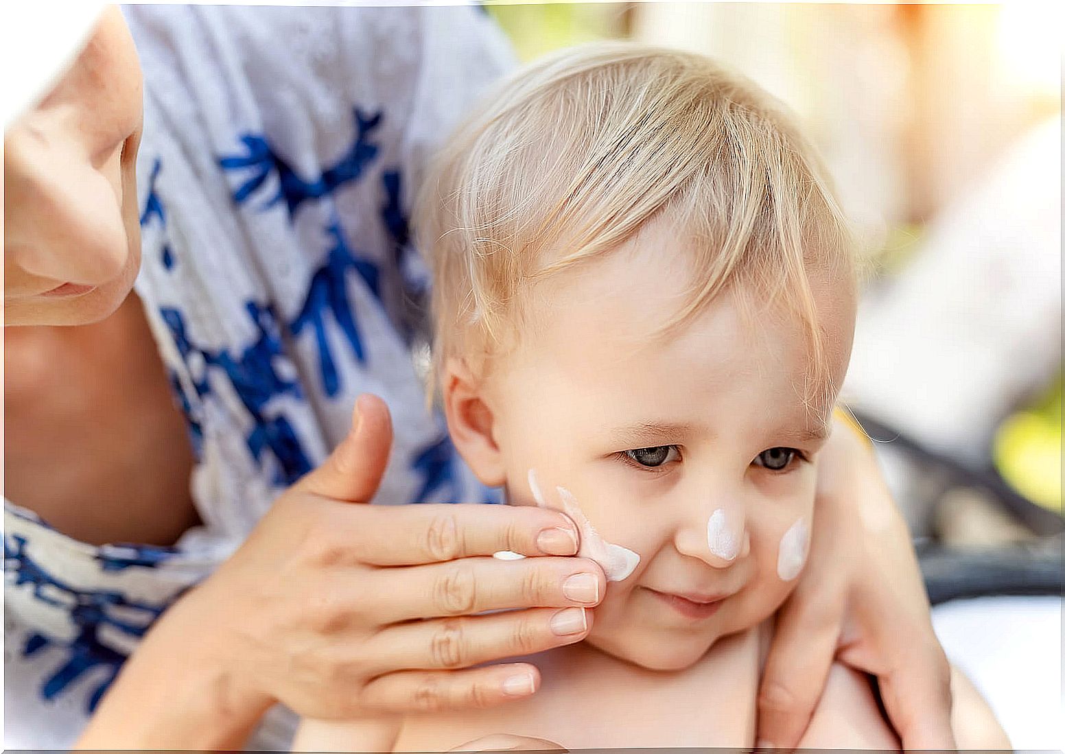 Grandmother applying sunscreen to her grandson to prevent pityriasis alba.