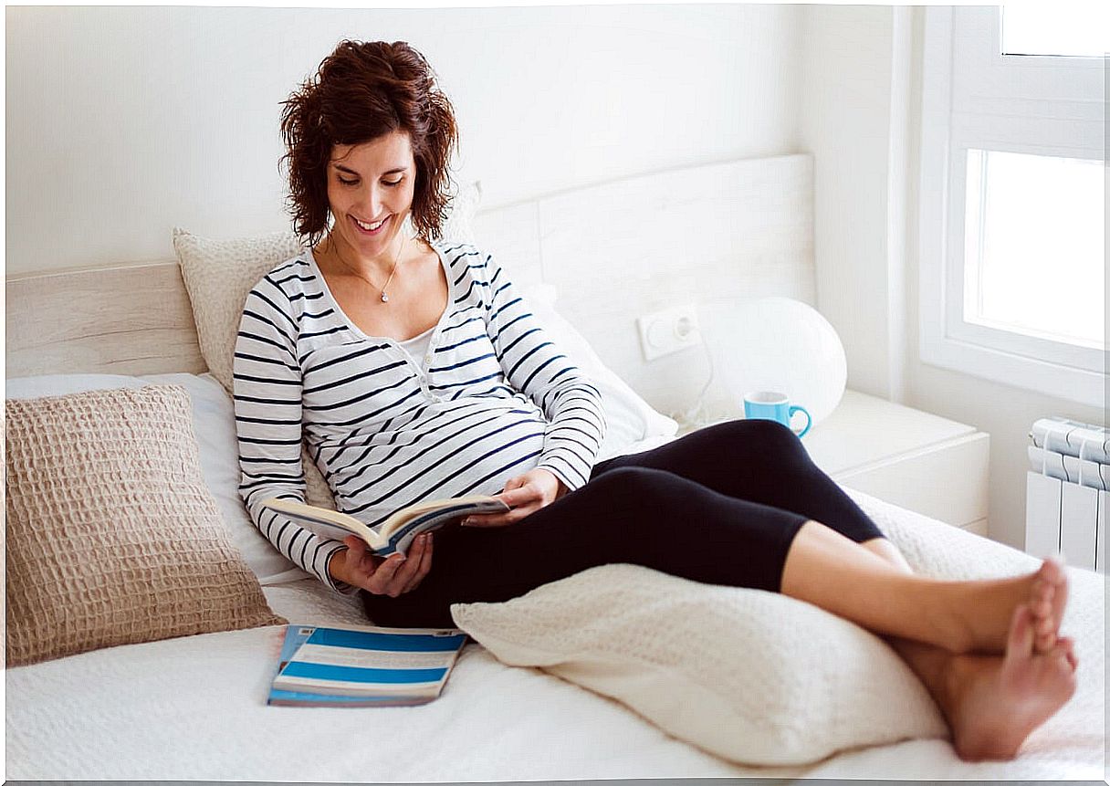 Pregnant woman reading with her legs up.