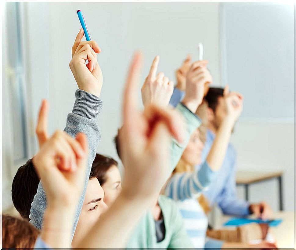 Students raising their hands in class to learn, one of the pillars of education.