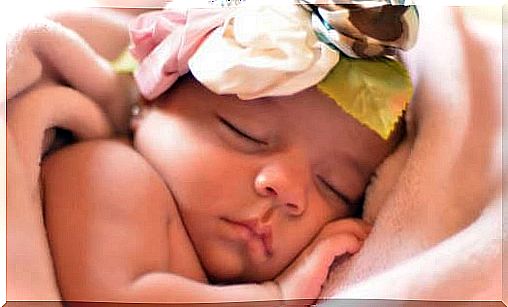 A sleeping baby with a flower hat