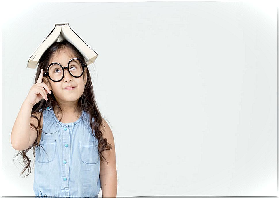 Little girl with a book on her head putting thinking-based learning into practice.