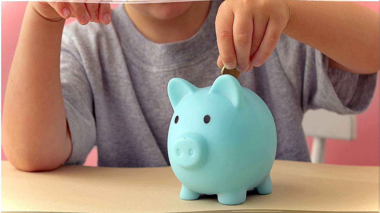 Child putting money in a piggy bank.